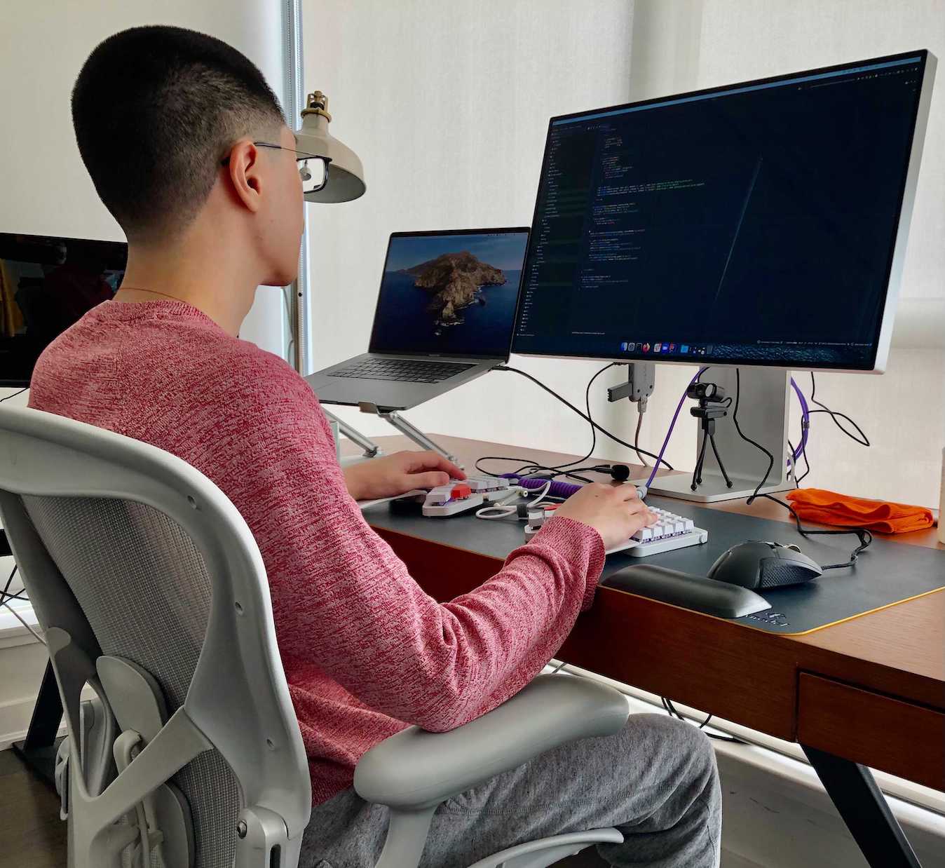 A team member sitting down working from home with their laptop and monitor.